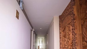 A hallway with a patterned carpet, a wooden carved panel on the right, and a recessed ceiling light. - Green Paradise Hotel (Yangon)