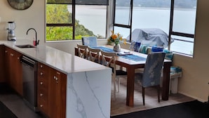 A kitchen with a marble countertop, wooden cabinets, and a view of a lake. - Gorgeous Waterfront Views and Private Access to Bay (Wyuna Bay)