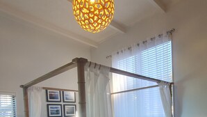A four-poster bed with white bedding and a blue blanket, a wooden nightstand, and a wall-mounted light fixture. - Gorgeous Waterfront Views and Private Access to Bay (Wyuna Bay)
