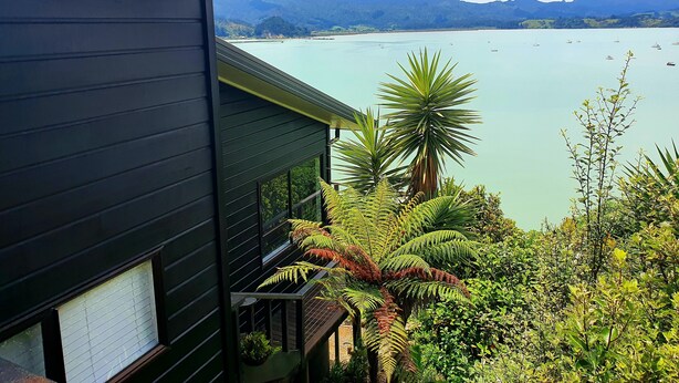 A modern building with a balcony overlooking a calm lake and distant mountains. - Gorgeous Waterfront Views and Private Access to Bay (Wyuna Bay)