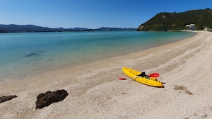 A beach with a kayak and a clear view of the water and distant mountains. - Gorgeous Waterfront Views and Private Access to Bay (Wyuna Bay)
