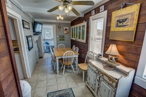 Un coin repas avec une table et des chaises en bois, un ventilateur de plafond et un téléviseur.