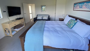 A bedroom with a bed, a TV, a desk, and a door.