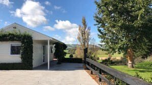 A single-story house with a covered porch, a concrete driveway, and a wooden fence.