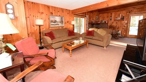A cozy living room with wooden walls, a sofa, a coffee table, and a television. - Beautiful Waterfront Home w/ Canoe & 1 Person Kayak. Close to North Conway (Madison)