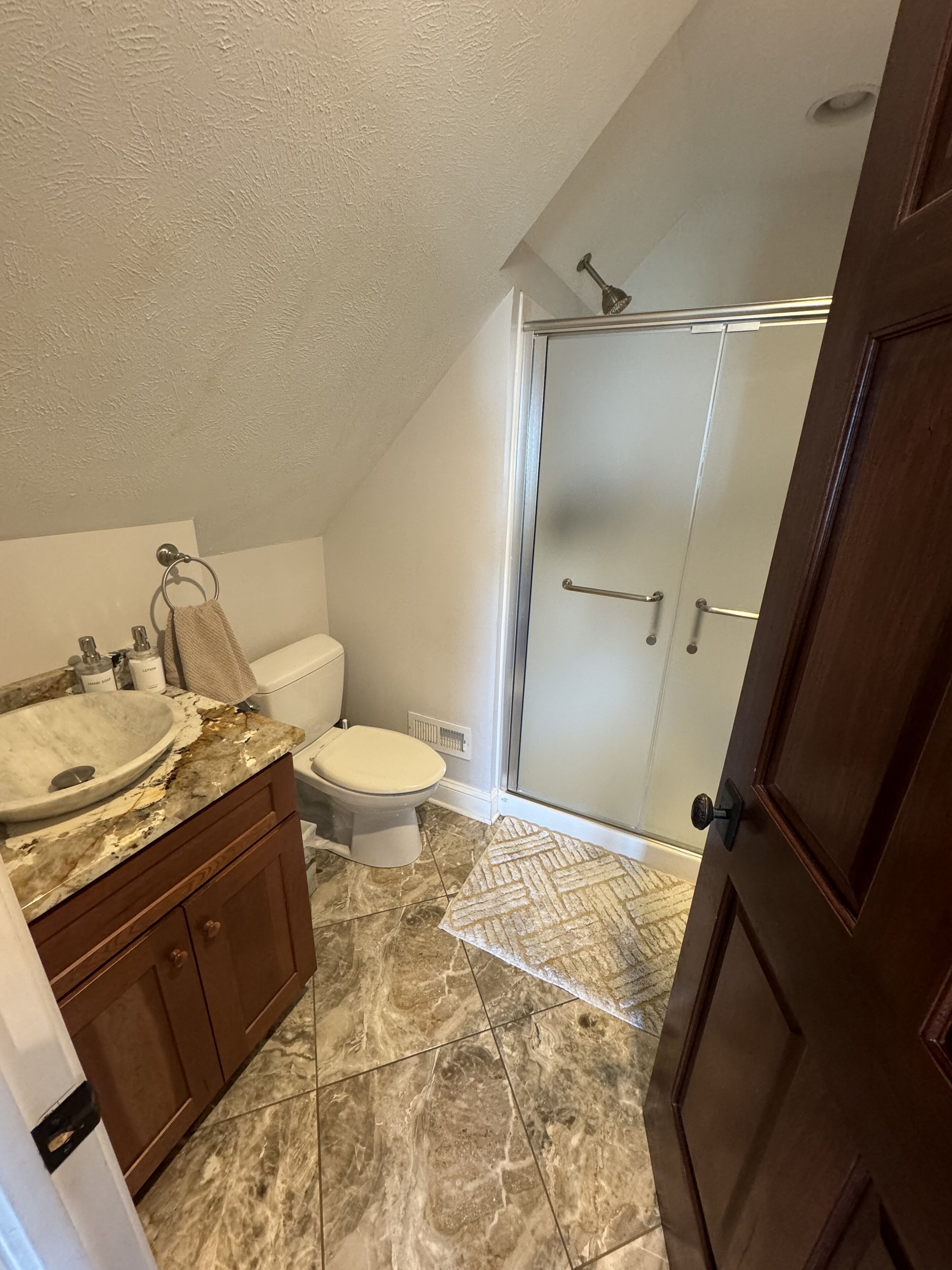 A bathroom with a marble sink, toilet, and shower.