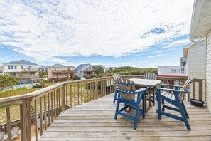 A wooden deck with outdoor furniture, a view of neighboring houses, and a clear sky.