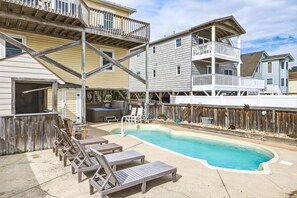 Zona residencial con piscina, sillas de descanso y una terraza de madera.
