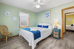 A bedroom with a bed, a chair, a nightstand, and a ceiling fan. - Six Pack | 1169 ft from the beach | Dog Friendly, Private Pool, Hot Tub | Nags Head (Nags Head)