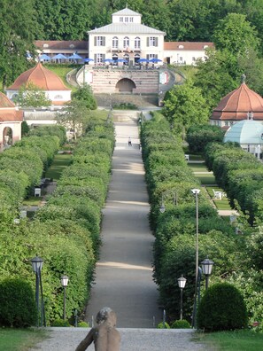 A pathway leading to a building with a central archway, surrounded by greenery and benches. - Apartment "Am Klosterberg" Bad Brückenau  (Bayern - Bad Brückenau)