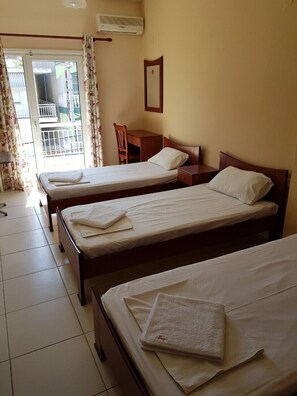 Ein Hotelzimmer mit zwei Einzelbetten, einem Schreibtisch und einem Stuhl.