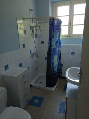 Un bagno con doccia, lavabo, WC e mobiletto.