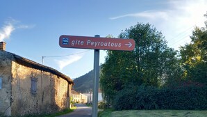 Une route de campagne avec un panneau indiquant « gîte Peyroutous » sur la droite.