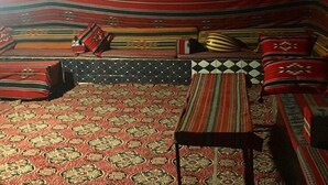 A room with a patterned carpet, a sofa with cushions, and a small table. - Um Al Tawaqi (Wadi Rum)