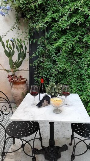 Mesa al aire libre con una botella de vino, dos copas y un bol de comida.