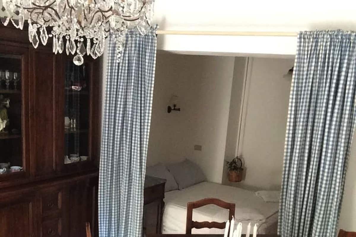 Un coin repas avec une table en bois, des chaises, un lustre et des rideaux à carreaux.
