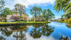 A residential area with houses, a calm lake, and trees. - Lake View ~ Private Patio ~ Golf Cart ~ Pool (Miramar Beach)