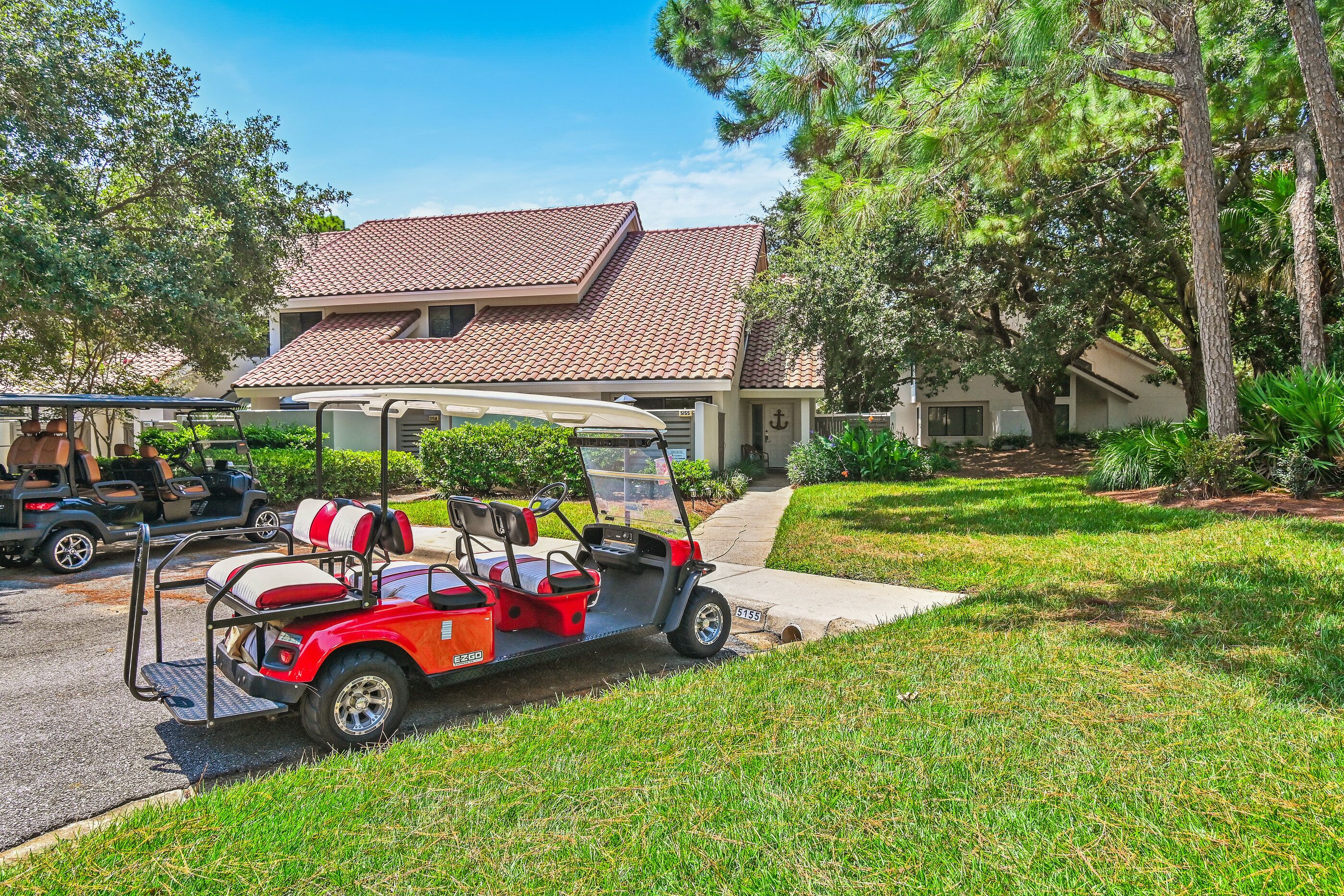 A residential property with a two-story house, a driveway, and a red golf cart parked in the driveway.