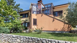 Een tweelaags huis met een glazen conservatorium, een stenen muur en een stenen trap die naar de ingang leidt.
