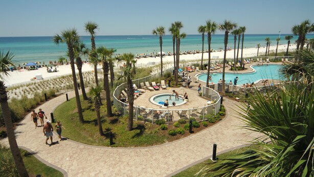 A resort with a central pool, palm trees, and a beach area. - Grand Panama Resort Direct Beachfront 3 Bed with Bunks and Amazing Views (Panama City Beach)