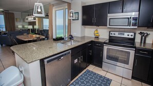 A modern kitchen with granite countertops, stainless steel appliances, and black cabinetry. - Grand Panama Resort Direct Beachfront 3 Bed with Bunks and Amazing Views (Panama City Beach)