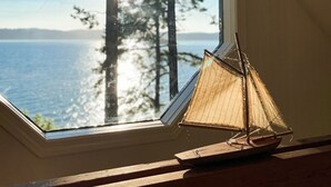 Une lucarne offrant une vue sur une forêt et un plan d’eau.