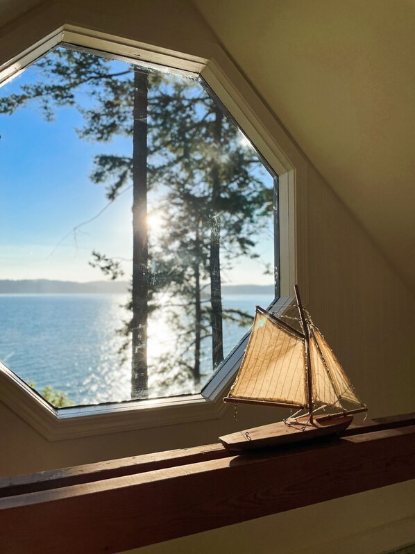 Ein Dachfenster mit Blick auf Wald und Wasser.