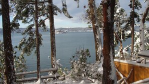 Une terrasse enneigée offrant une vue sur un lac et des montagnes lointaines.