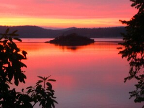 Ein ruhiger See bei Sonnenuntergang mit einer kleinen Insel in der Mitte.