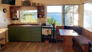 Une cuisine chaleureuse, avec des meubles en bois, un poêle et une vue sur la mer.