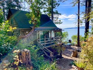 Eine rustikale Holzhütte mit Veranda, die auf einen See mit Blick auf einen dichten Wald blickt.