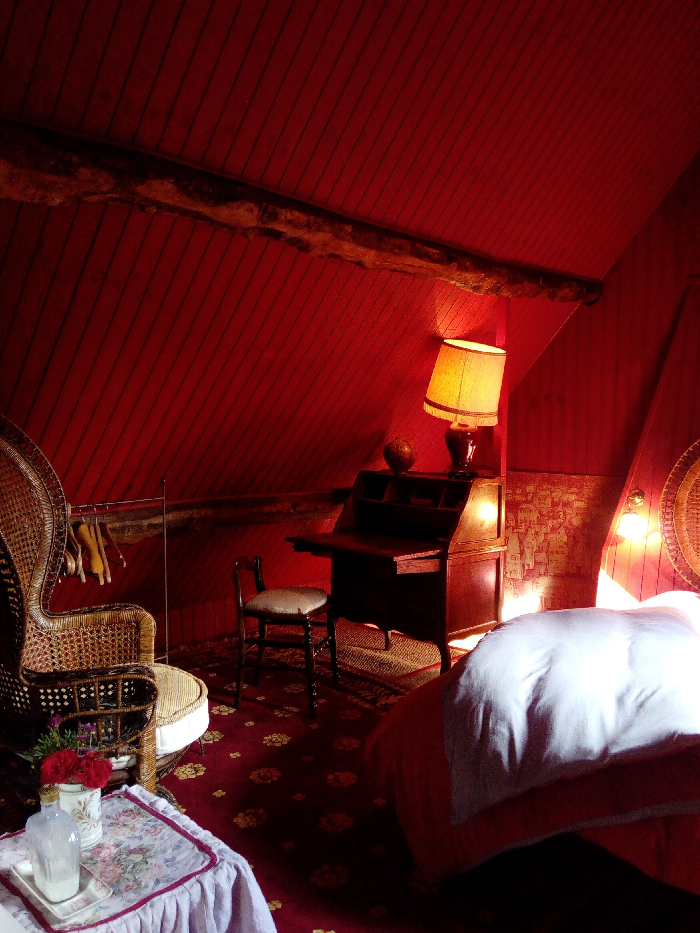 A cozy room with a bed, a desk, a chair, and a lamp.