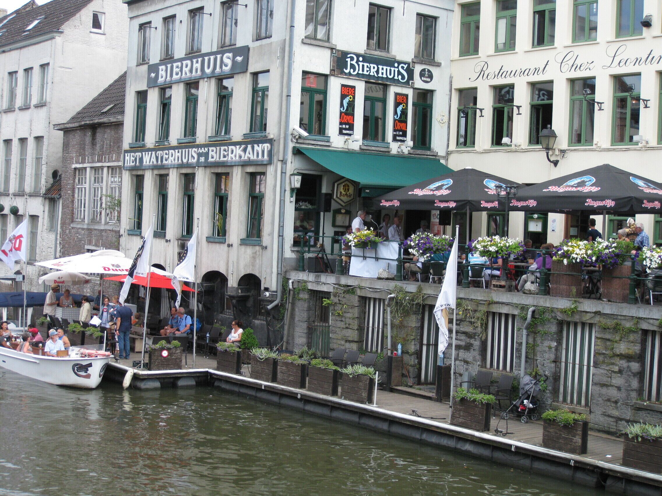 A riverside bar with outdoor seating and a docked boat.