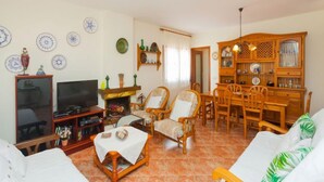 Ein gemütliches Wohnzimmer mit Fernseher, Kamin, Esstisch und Stühlen.