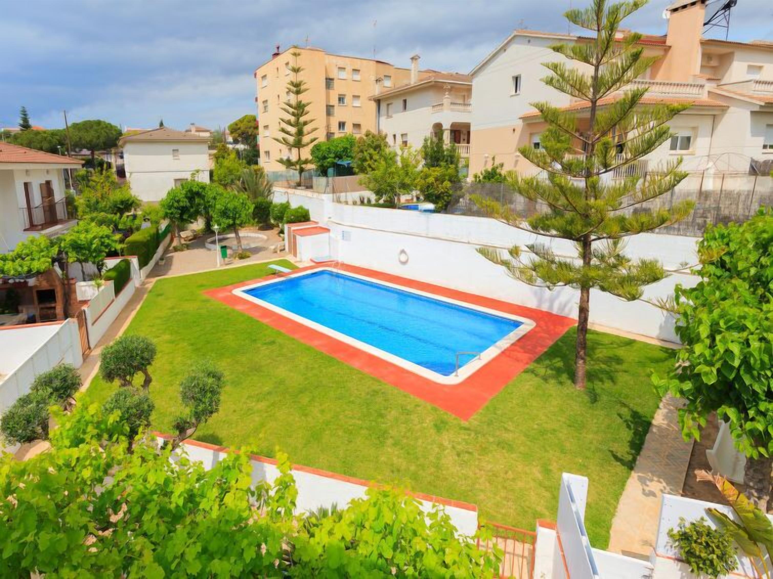 Un quartier résidentiel doté d’une piscine, entourée d’une pelouse bien entretenue et de divers arbres.