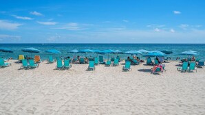 A beach with rows of turquoise lounge chairs and umbrellas, a sandy beach, and the ocean in the background. - Tides Miami 1BR +den Condo on the beach (Hollywood)