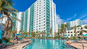 A hotel with a large swimming pool surrounded by palm trees and lounge chairs. - Tides Miami 1BR +den Condo on the beach (Hollywood)