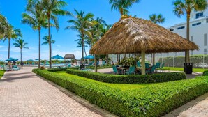 A resort with a thatched-roof pavilion, palm trees, a pool, and a well-maintained garden. - Tides Miami 1BR +den Condo on the beach (Hollywood)
