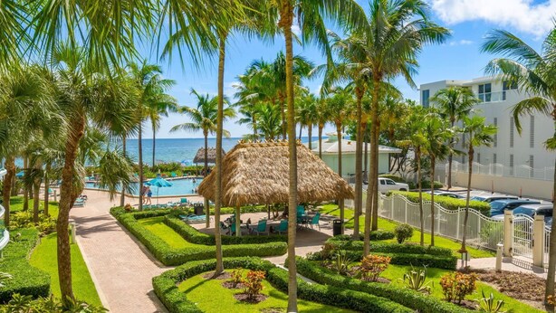 A resort with a pool area, palm trees, and a view of the ocean. - Tides Miami 1BR +den Condo on the beach (Hollywood)