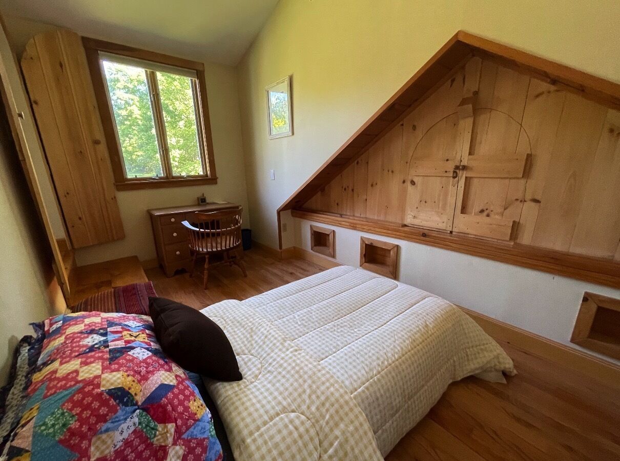 Un dormitorio con cama, escritorio y ventana.