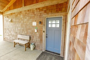 A wooden building with a blue door, a bench, and a small trash bin.