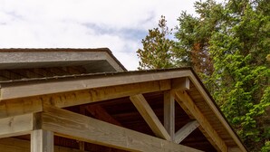 A wooden cabin with a covered porch, a bench, and a door. - Lookout House - Romantic Luxury and Ocean Views (Gold Beach)