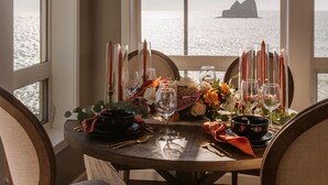 A dining table set for two with candles, glasses, and a view of the sea. - Lookout House - Romantic Luxury and Ocean Views (Gold Beach)