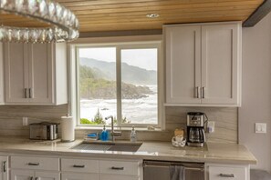A kitchen with a view of the ocean, a coffee maker, and a toaster.