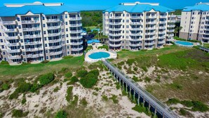 A high-rise hotel with multiple balconies, a central pool, and a bridge connecting the buildings. - 5 Ocean Place -1st Floor Oceanfront 3 BR Condo Next Door to The Ritz Carlton. (Fernandina Beach)