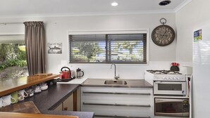 Una cocina moderna con estufa a gas, horno, microondas y una ventana con persianas.