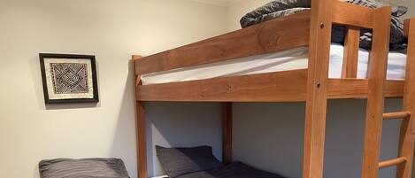 A bunk bed with a wooden frame, grey bedding, and a ladder.