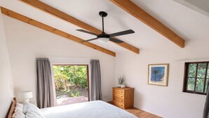 A bedroom with a bed, wooden beams, a ceiling fan, a window, and a dresser. - Matapouri Hideaway - Matapouri Holiday Home (Matapouri)