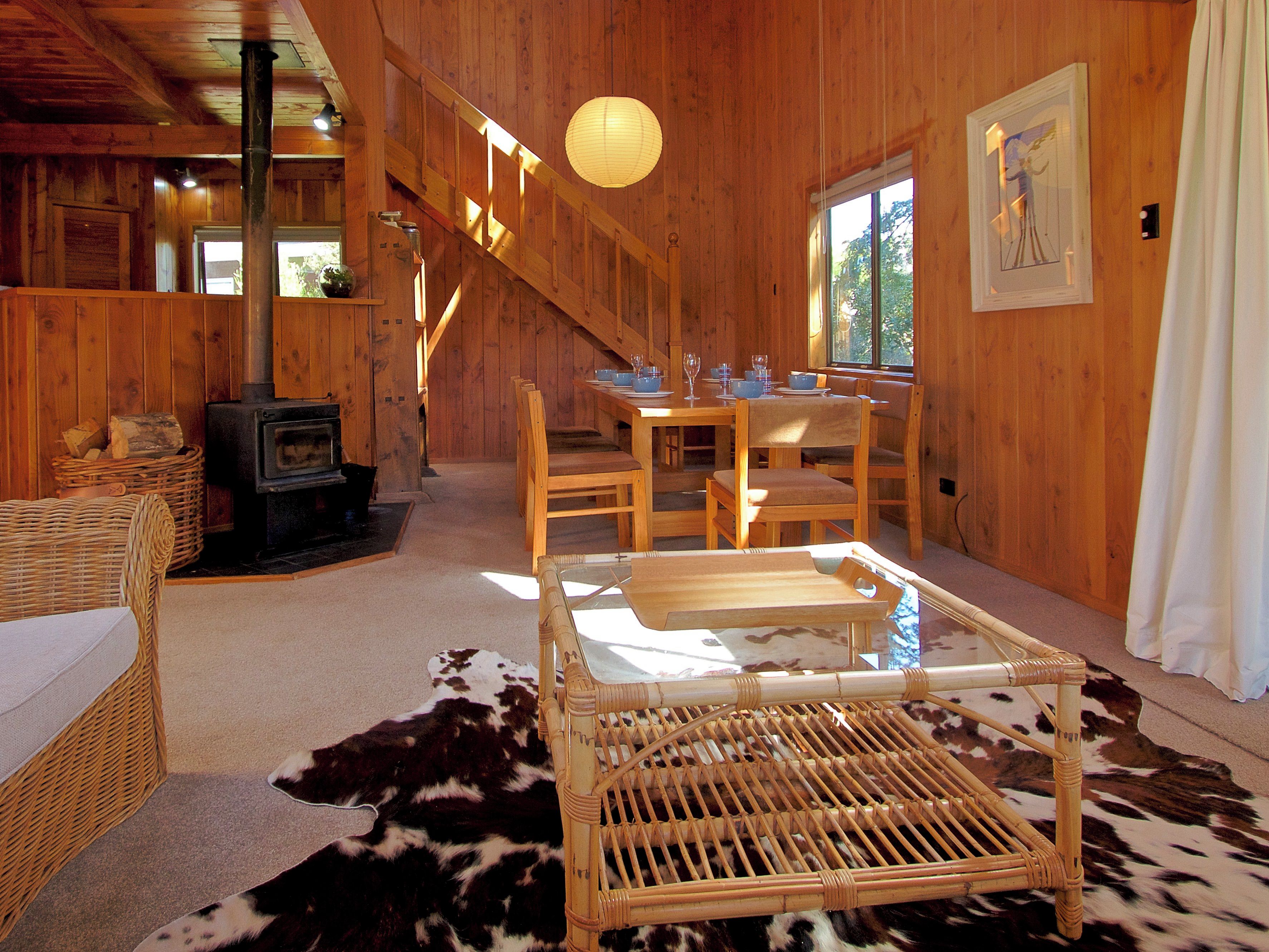 A wooden interior with a fireplace, dining area, and staircase.