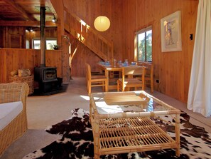 Un interior de madera con chimenea, comedor y escalera.